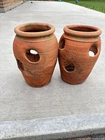 Front view of both terracotta strawberry planters showing side pockets and surface wear