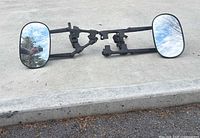 Both strap-on towing mirrors laid flat showing mirror faces and mounting arms