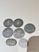 Fronts of seven Hamilton merchant tokens showing crests and legends