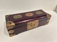 Closed jewelry box showing brass hardware and lid medallions