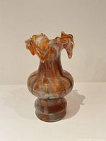 Front view of orange/amber and white swirl art glass vase showing ruffled rim and bulbous shape
