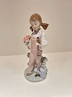 Front view of Lladró figurine showing girl with bouquet, bird, watering can and flowers