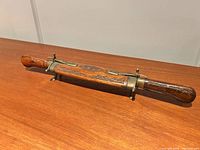 Carved hardwood and brass sheath holding knife and fork ends concealed