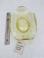 Top view of oval yellow glass console bowl showing starburst base and handles next to ruler for scale