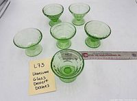 Six green footed dessert bowls arranged with measuring ruler