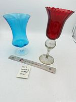 Blue and red glass vases side by side with ruler for scale