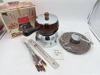 Complete fondue set displayed with box, pot on stand, trivet, forks, ruler for scale