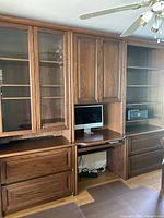 Front view showing full wall unit with desk center, glass cabinets left