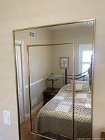 Front view of rectangular brass framed mirror on wall