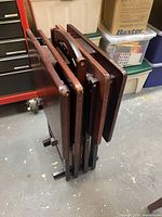 set of four folded tray tables on storage stand