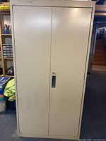 Front view of beige metal cabinet showing full height double doors