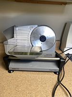 Front view of Waring Pro food slicer showing blade, tray, carriage and power cord