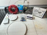 Group shot of all items on table: wafer light, Taloya fixture, Leviton outlet bag, fish tape reel, driver box, pigtails, connectors