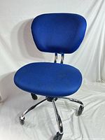 Full view of blue armless mesh office chair, chrome base, casters visible