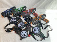 Four Armogear blasters and four sensor vests laid out showing colours and straps