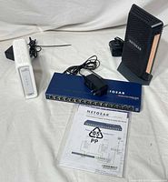 All three networking devices with power adapters and manual visible