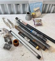 Overall lot showing pipe nipples, fittings, packaged parts, tool