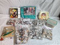 Assorted boxed puzzles, wooden puzzle and multiple bags of loose pieces displayed on surface