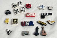 Group image of 19 assorted Crocs shoe charms arranged on white cloth
