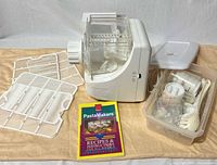 All items laid out including pasta maker, racks, booklet, container of accessories