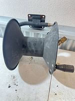 side view of black plastic spool on metal wall bracket with hose connection