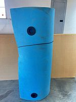 Blue foam log standing vertically showing cylindrical shape and black end plug