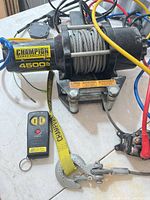 Overall view of Champion 4500 lb winch with cable, hook strap, remote, roller fairlead and wiring harness