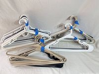 Bundle of assorted white, beige and black plastic clothes hangers