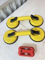 Top view of two yellow dual suction cup lifters and red FastCap tool