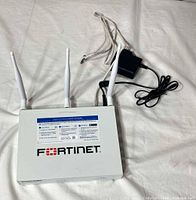 Top view of Fortinet FortiWiFi 40F with three antennas, power adapter and Ethernet cable