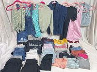 Overview of hanging garments and folded stacks on white backdrop