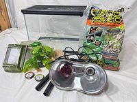 All items overview: glass terrarium, heat lamp fixture with red bulb, Eco Earth substrate bag, travel tank, fake plant, gauges, mounting poles