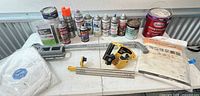 Overall view of paint cans, spray cans, Tyvek suit, ZipWall kit, clamps and poles