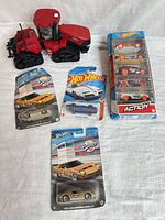 All items together: red Case IH tractor, three individual Hot Wheels cards, one Hot Wheels Action 5-pack