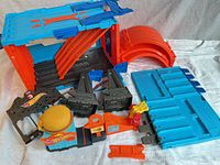 All track and accessory components laid out including blue panels, orange curves, black assemblies, gate, burger stand, launcher and connectors