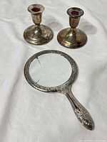 Handheld mirror and two candlesticks front view
