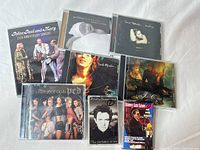 Group shot of seven CDs and one cassette showing cover art and cases