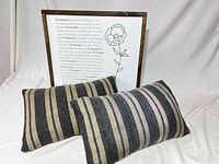 Two striped lumbar pillows with framed quote sign behind