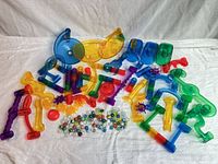 array of loose translucent plastic marble run parts and marbles spread on cloth