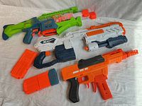 Overview of four dart blasters and two magazines laid out on fabric backdrop