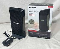 Modem standing upright with power adapter and box