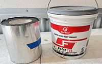Pail of Red Devil sealant beside foil-faced butyl tape roll