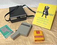 Group shot of camera, case, film box, Photojojo book and manual