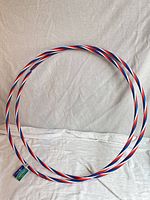 Two red white and blue spiral plastic hula hoops laying flat, tag visible