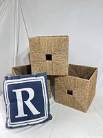 three seagrass baskets stacked with navy blue letter R pillow