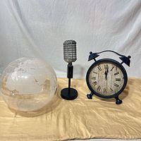 Group shot showing metal clock, clear plastic globe, metal microphone decor