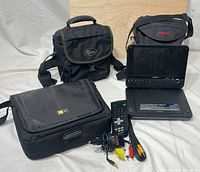 Overall lot showing DVD player, remote, cable, power adapter and three carry bags