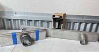 Long stainless steel channel drain, shorter drain with strainer, door holdback/stop shown together