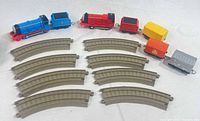 Full lot showing two locomotives with tenders, three freight cars and ten curved track pieces
