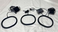 Three black ring charging bases each with attached AC adapter